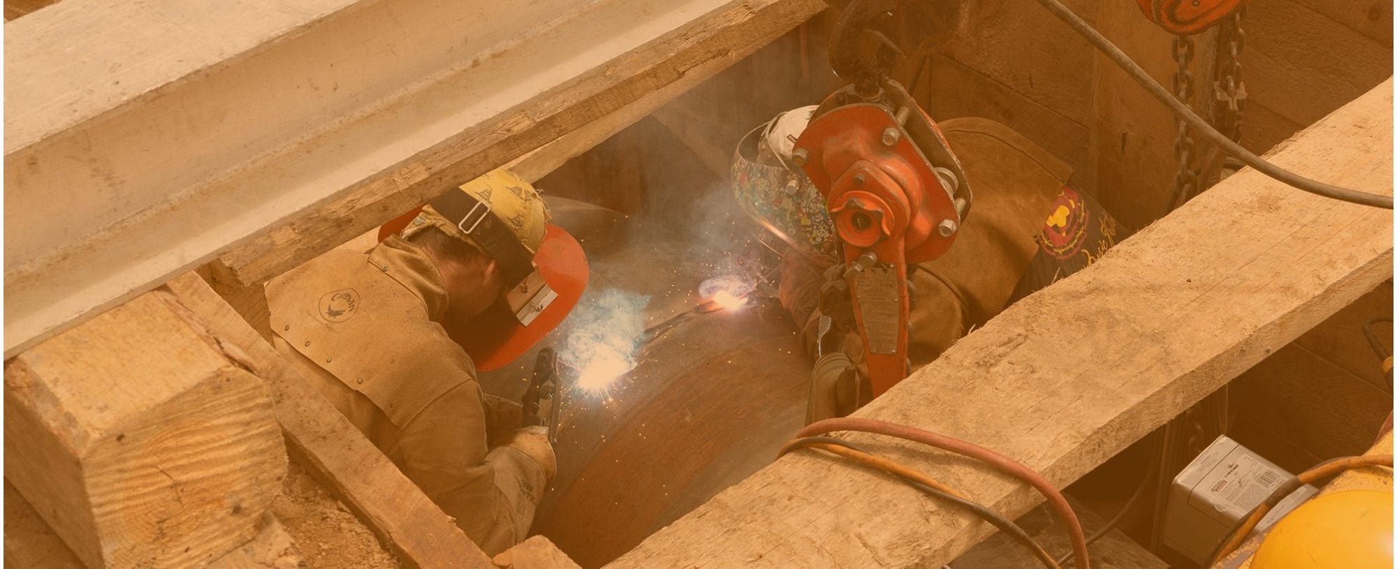 Two men stick welding a pipe