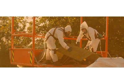 Two people in asbestos protective equipment throw asbestos away